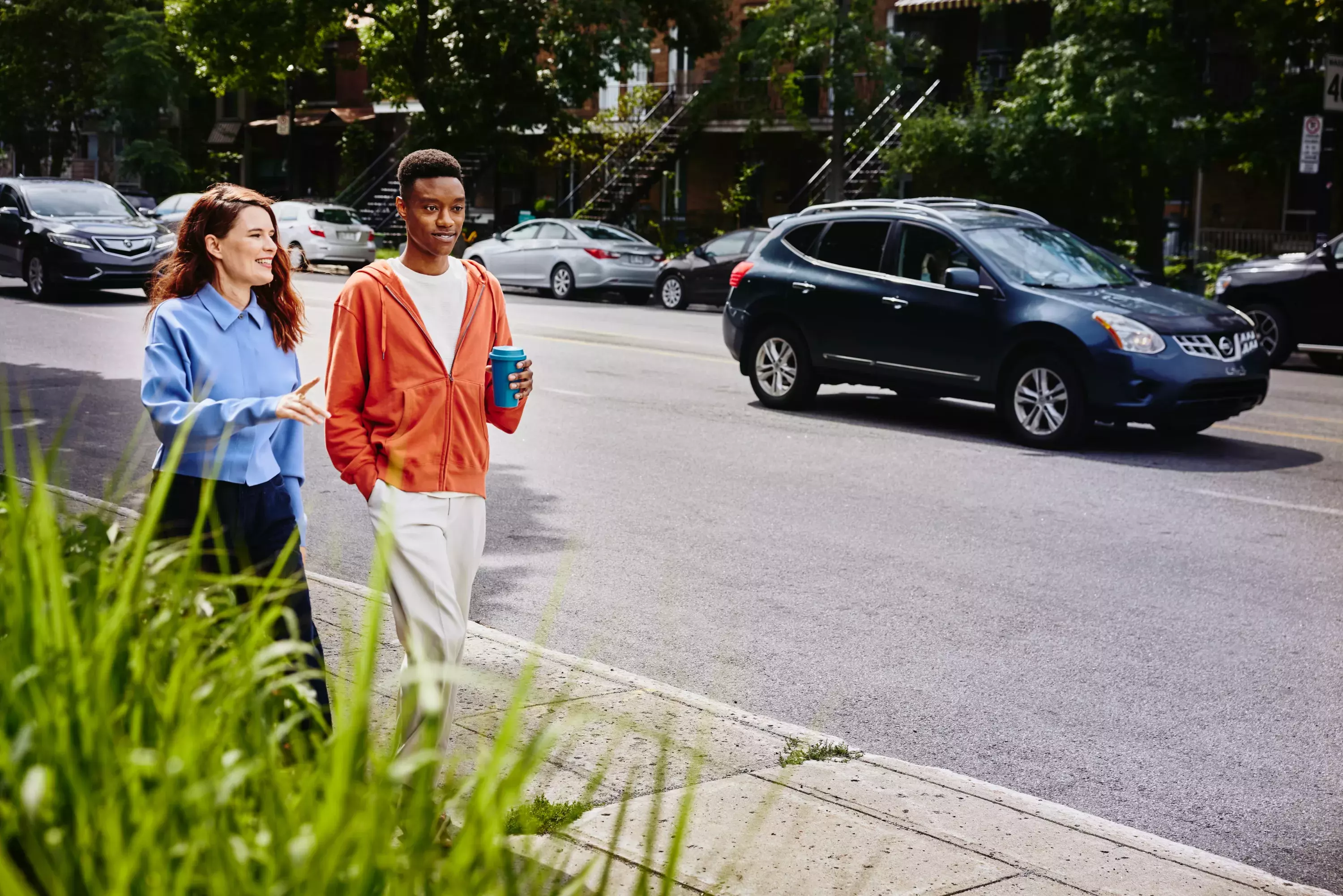 Female and male, with coffee mug, walking on sidewalk in a street