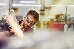 male wearing safety glasses, grinding metal
