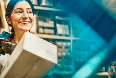 Smiling woman looking away while scanning a package in a warehouse