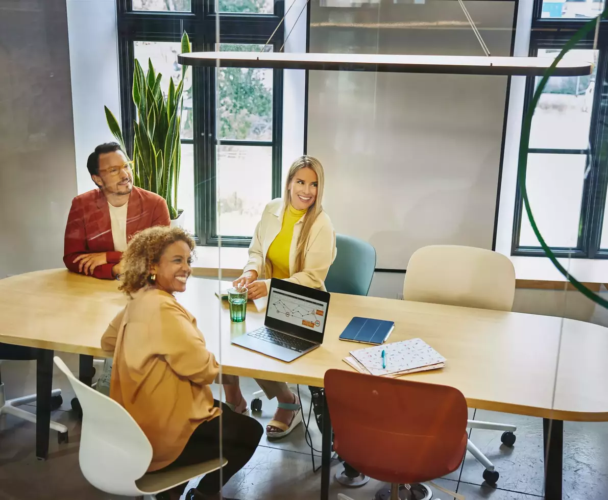 Group of people sitting at a oval table, having a meeting