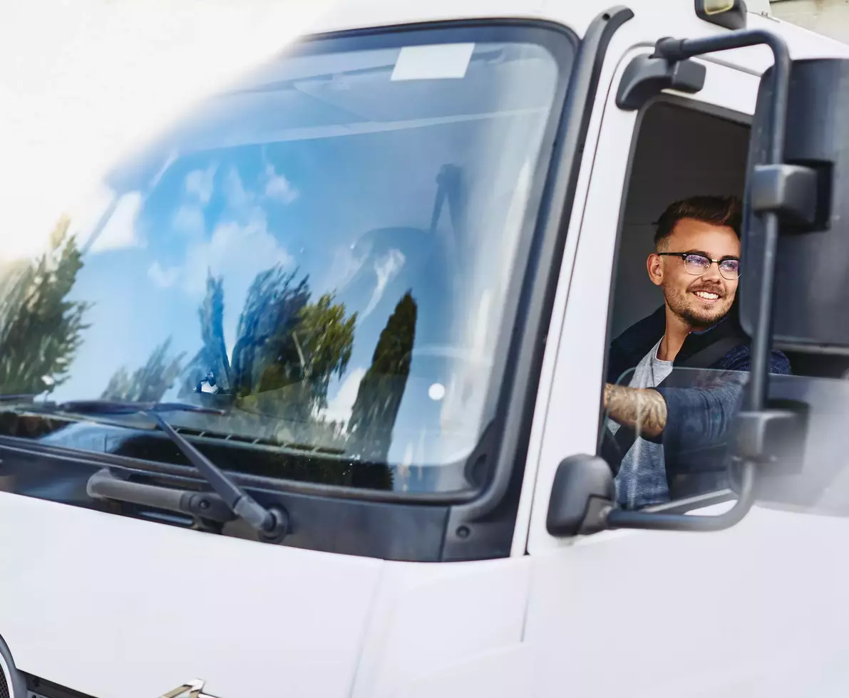 homme souriant conduisant une camionnette de livraison