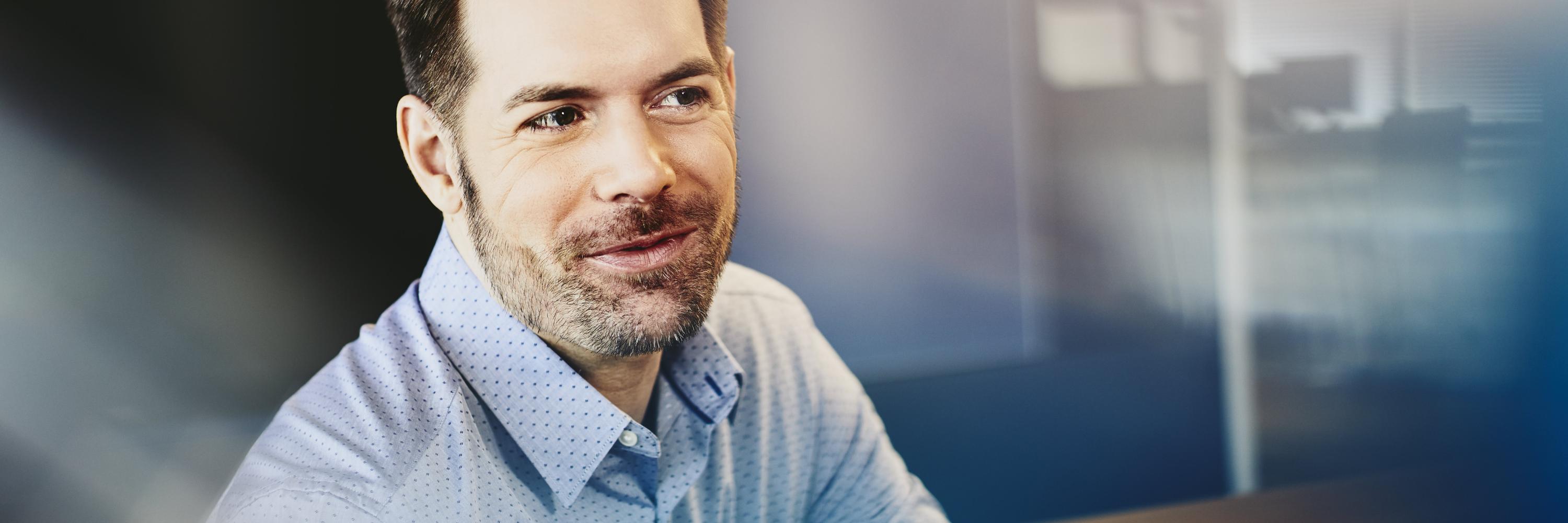 Man in a shirt in an office. Primary color: blue. Man in a shirt in an office. Primary color: blue.